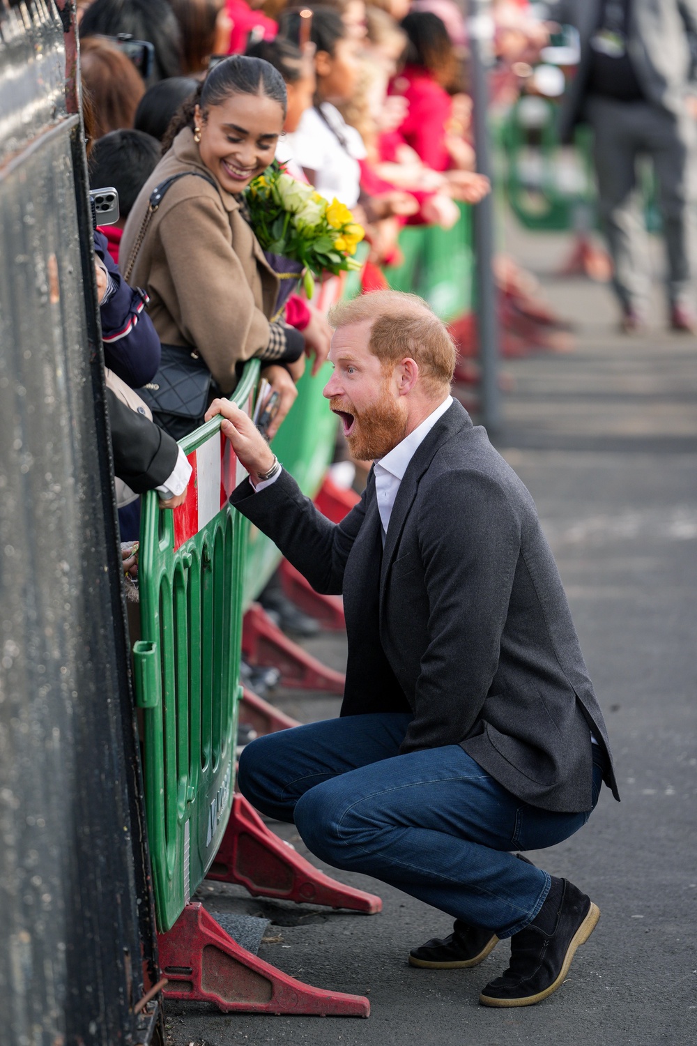 Prince Harry animatedly talking to a group of children (Getty)