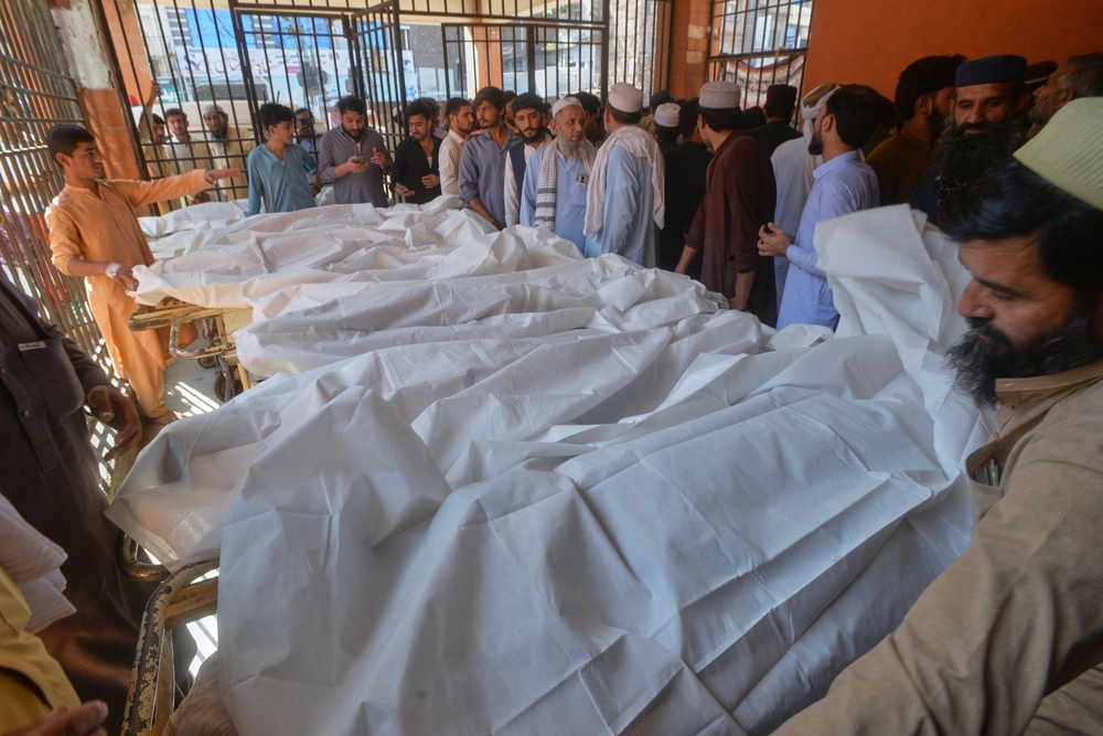 Parents gather at a hospital next to the bodies of children who died in the roof collapse of a private school (AP)