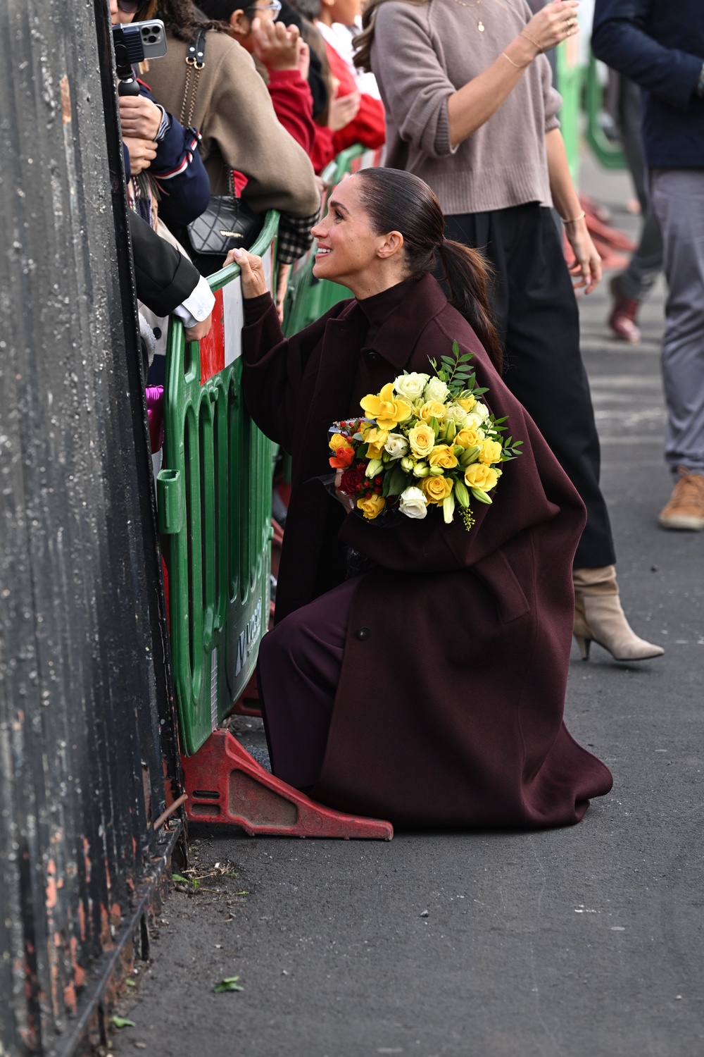 Meghan crouches down to meet a youngster (Doug Peters/PA) (PA Wire)