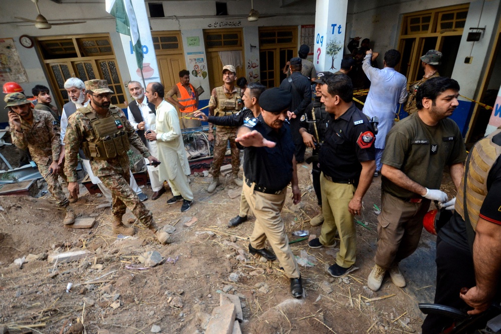 Police officers and military personnel gather as they are surveying the site of a school roof collapse (Reuters)