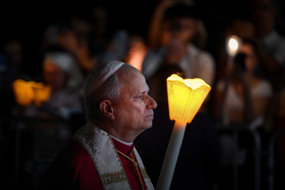 Pope Leo holds a candle as he takes part in a torchlight procession following the Rosary Prayer at the Shrine of Our Lady of Lourdes (AFP via Getty Images)