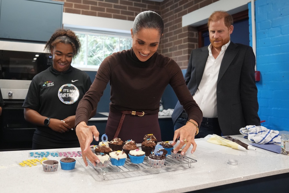 The Duke of Sussex watches as the Duchess of Sussex arranges birthday cupcakes (Joe Giddens/PA) (PA Wire)