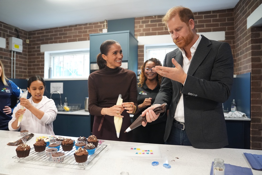 The Duke licks icing from his hand as he and the Duchess of Sussex decorate birthday cupcakes during a visit to Epic Partners in Nottingham (Joe Giddens/PA) (PA Wire)