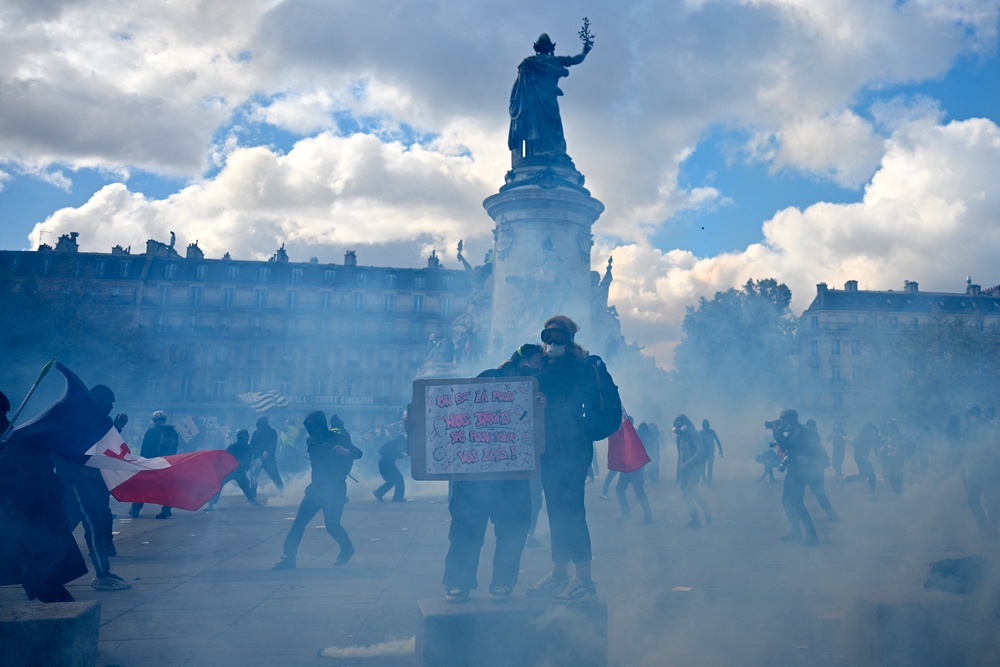 A protester holds a placard amid tear gas smoke as clashes erupt at Place de la Republique (AFP/Getty)