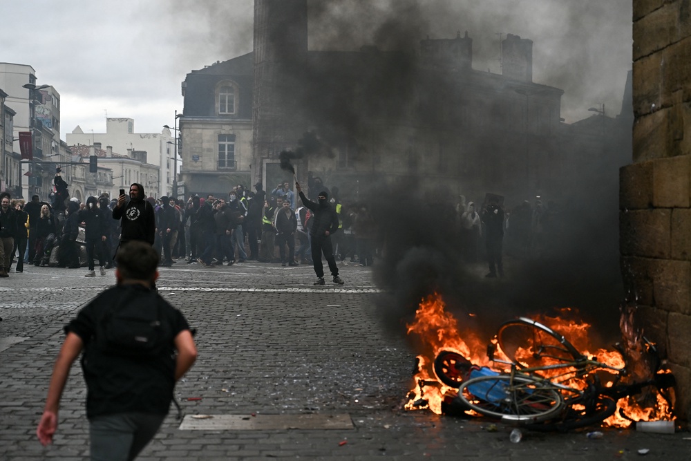 A protester lights smoke flares next to a fire during a demonstration to protest against the 'high cost of living' (AFP/Getty)