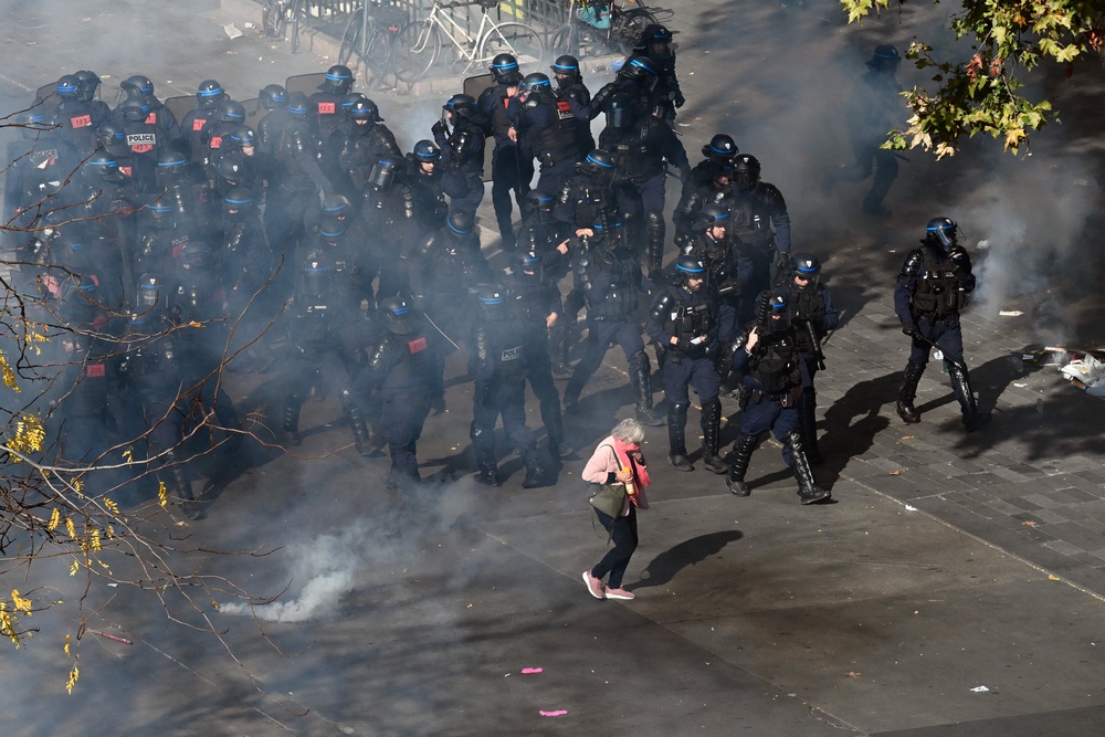 An elderly woman walks amid tear gas smoke past French police (AFP/Getty)