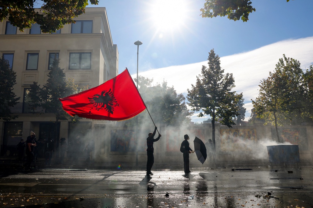 A protester holds an Albanian flag as he faces off with police water canon vehicles during an anti-government demonstration in central Tirana (AFP/Getty)