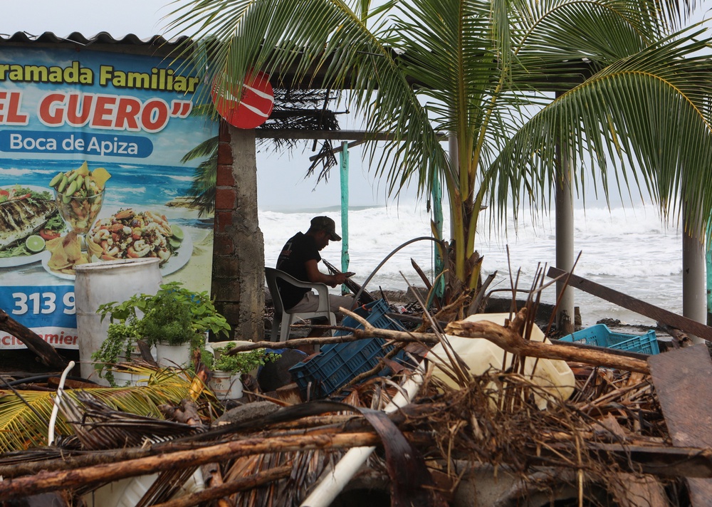 A man sits along the shoreline as Hurricane Trudy advances across the Pacific Ocean off Mexico's western coast, in Boca de Apiza, Michoacan state, Mexico (Reuters)