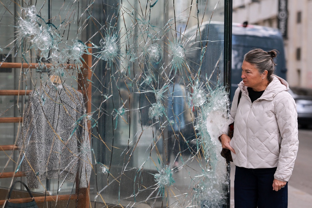 A person looks at the damaged glass of the Lacoste store on Champs-Elysees Avenue (Reuters)