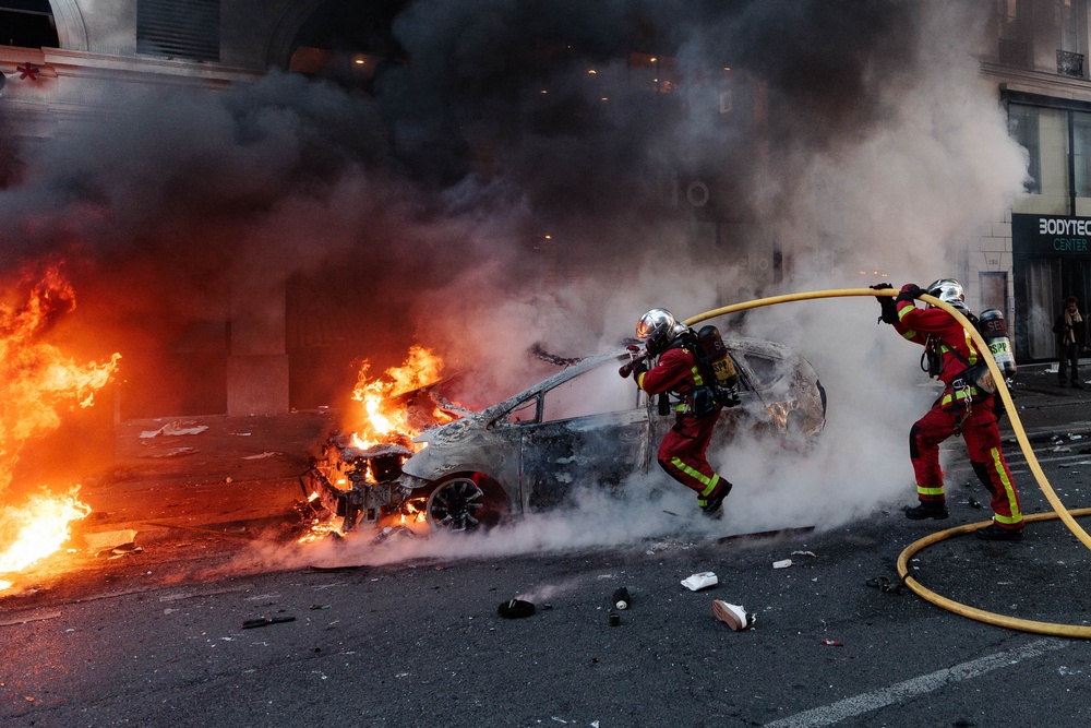 Firefighters respond to extinguish a car fire during violent clashes on the fringes of a protest in Paris (AFP/Getty)