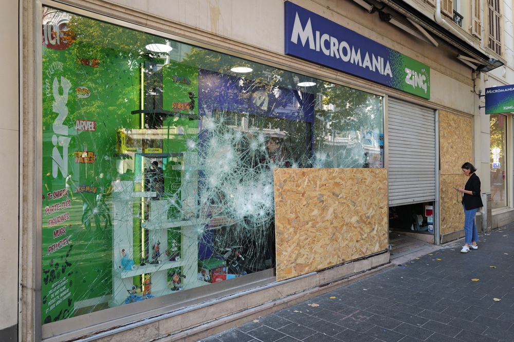 A woman stands next to a damaged Micromania-Zing video game retail shop at Jean-Medecin avenue in Nice (AFP/Getty)