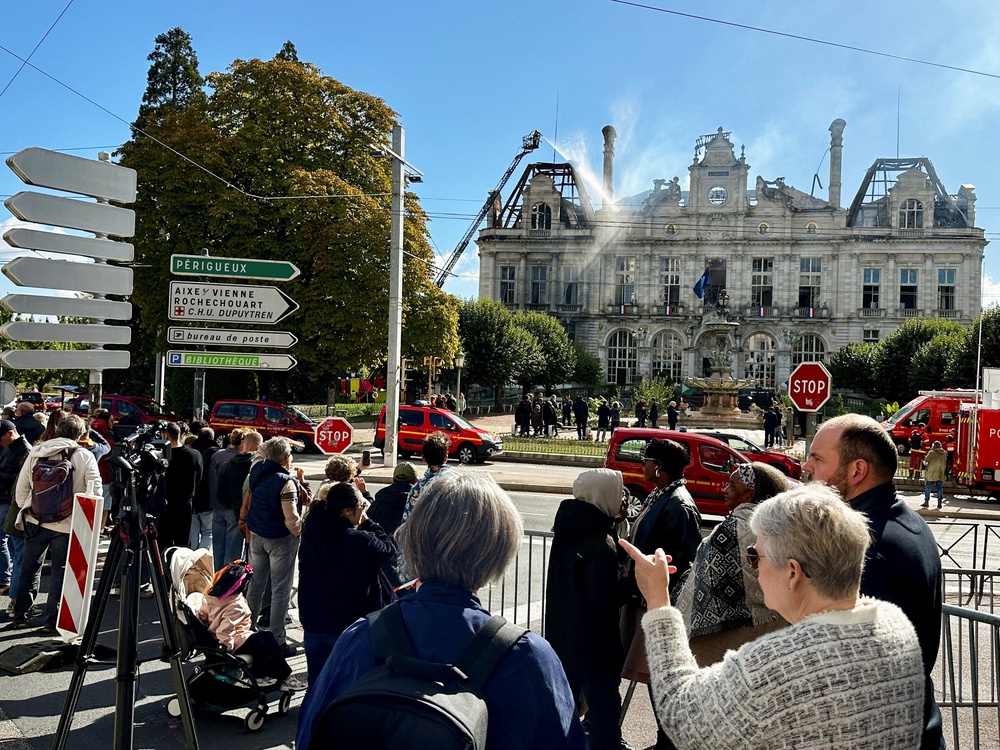 People stand as water is sprayed over the burnt and destroyed Limoges town hall, which was set ablaze and largely destroyed in an arson attack (Reuters)