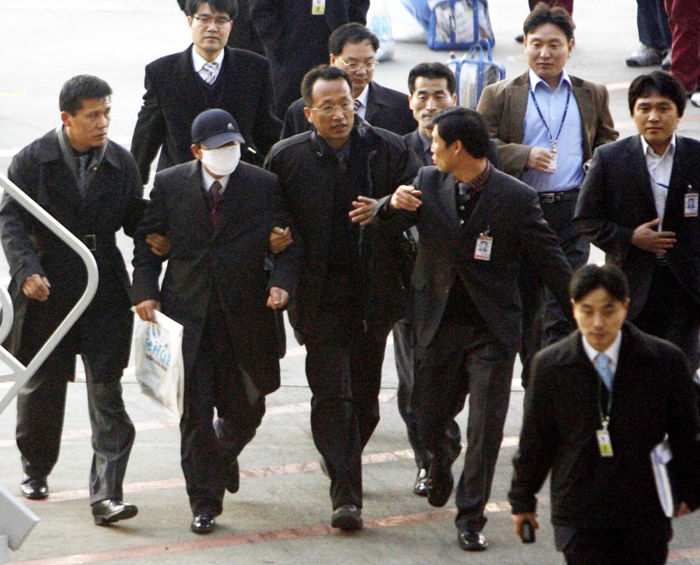 Prosecutors escort Jung Myong Seok, second left, off a plane upon his arrival at the Incheon international airport on 20 February 2008 (AFP/Getty)