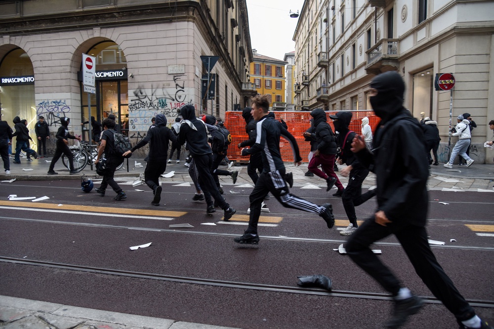 Protesters run along a street strewn with debris during a protest over the state of public services and the rising cost of living in Milan, on Sunday (Reuters)