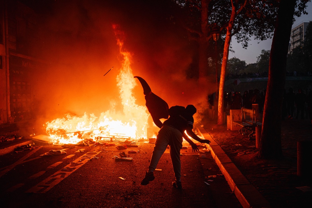 A protester feeds a fire with a material along the Canal Saint-Martin during ongoing protest action against the ‘high cost of living’, in Paris on 17 October (AFP/Getty)