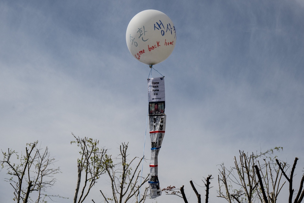 A floating balloon attached to a stand with writing that reads 
