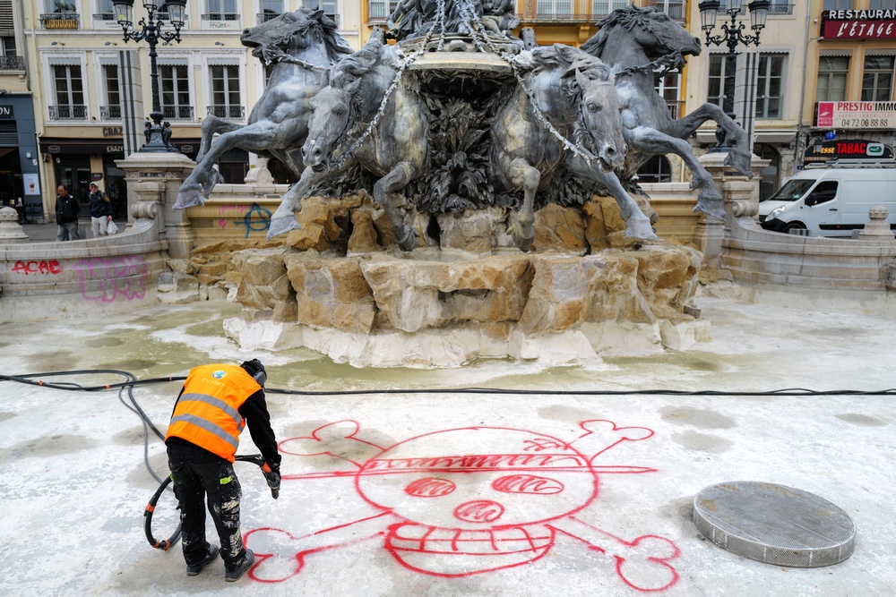A city hall employee removes a graffiti from the Bartholdi Fountain in Place des Terreaux, in Lyon (Koumal Lyon Republique)
