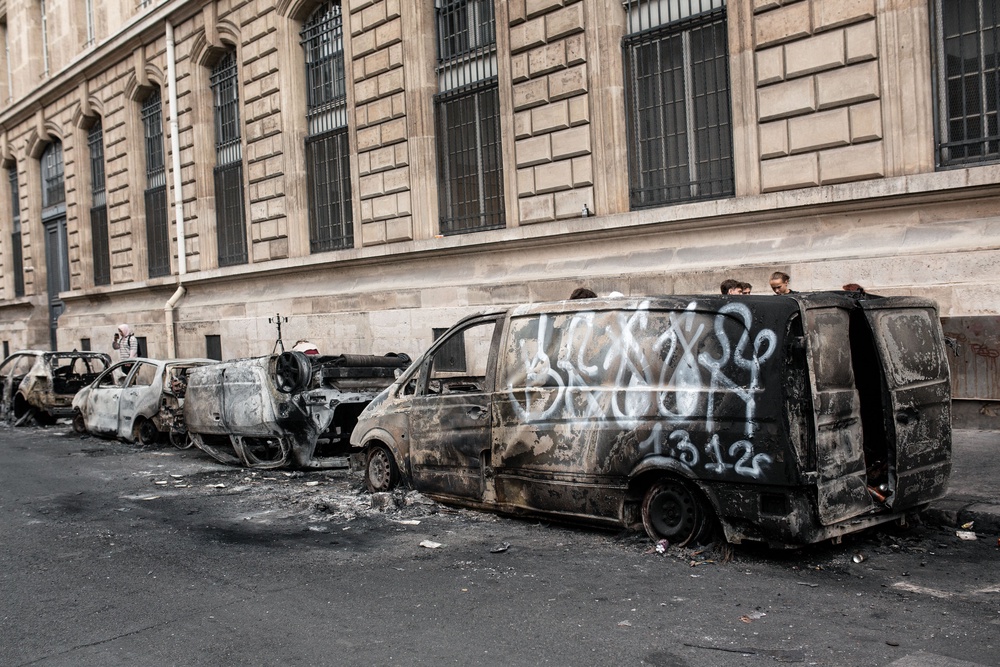 Several burned-out vehicles, including cars and a van covered in graffiti, line the pavement beside a stone building in Paris, France (AFP/Getty)