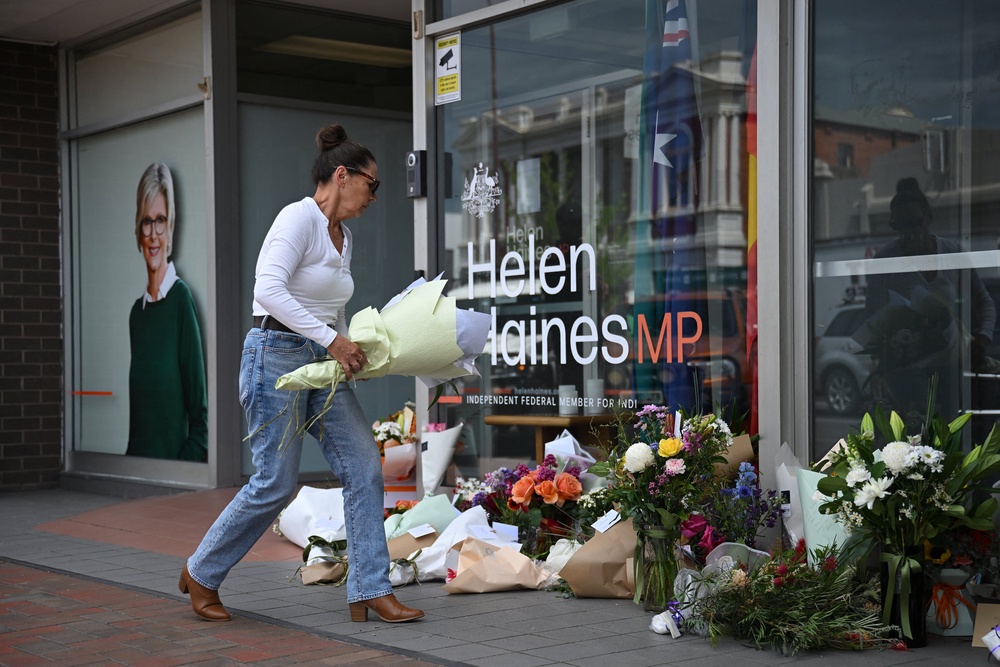 A woman leaves flowers outside the electoral office of independent Australian lawmaker Helen Haines, who was deliberately struck by a car outside her office on Monday (Reuters)