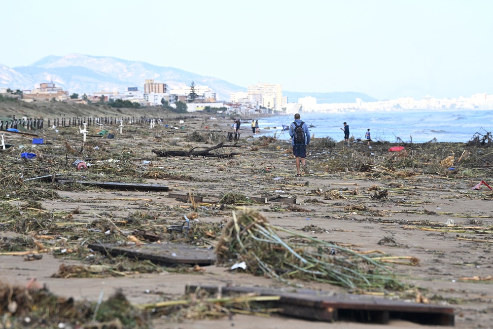 A man walks on the beach littered with debris following torrential downpours in Oliva, in the Valencia region, eastern Spain on 20 October (AFP/Getty)