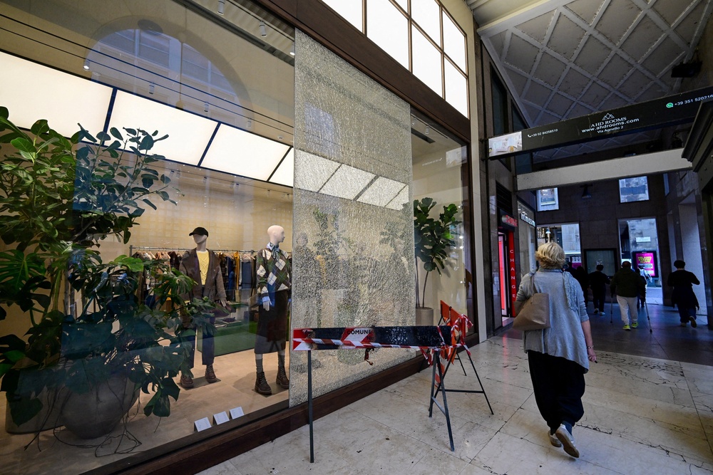 A woman walks past a shattered shop window cordoned off with safety barriers in a shopping passage following weekend clashes between police and protesters (REUTERS)