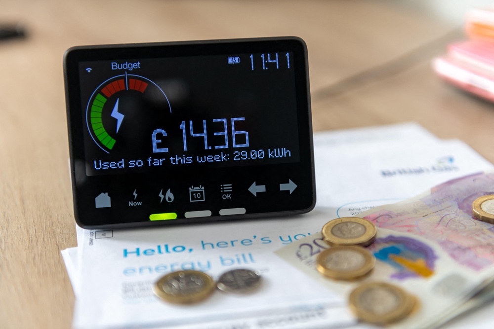 A smart energy meter showing latest reading surrounded by household energy bills and coins (Alamy/PA) (Alamy/PA)