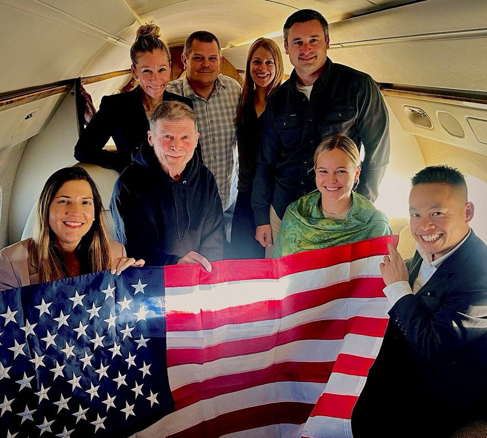 Stephen Hubbard, a 74-year-old US citizen held in Russian custody since 2022, poses with family members and US officials aboard a flight to the United States after his release from prison, in this handout photograph released on 21 October 2026 (Reuters)