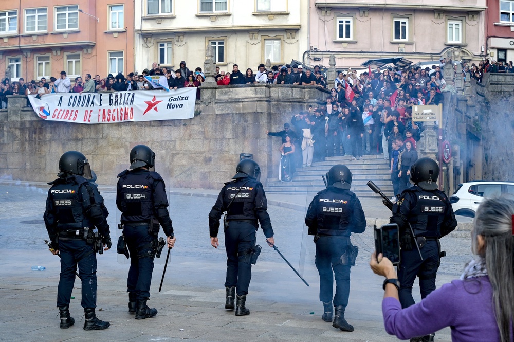 Police forces face protesters taking part in a demonstration against far-right during a meeting of Vox party's leader in Maria Pita square on Wednesday (AFP/Getty)