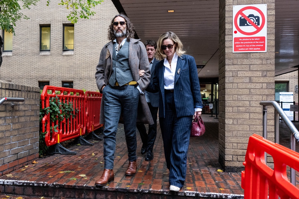 Russell Brand departs court with his wife Laura Gallacher (R) during his trial, where he faces rape and sexual assault charges at Southwark Crown Court on October 21, 2026 in London (Getty)