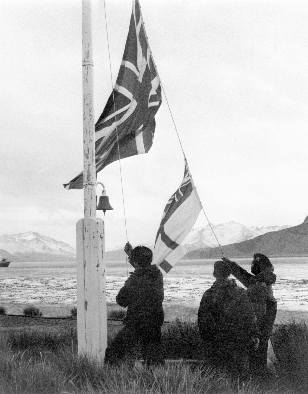 A Union Flag and white ensign being raised on South Georgia after the island's recapture by the British in May 1982 (PA)