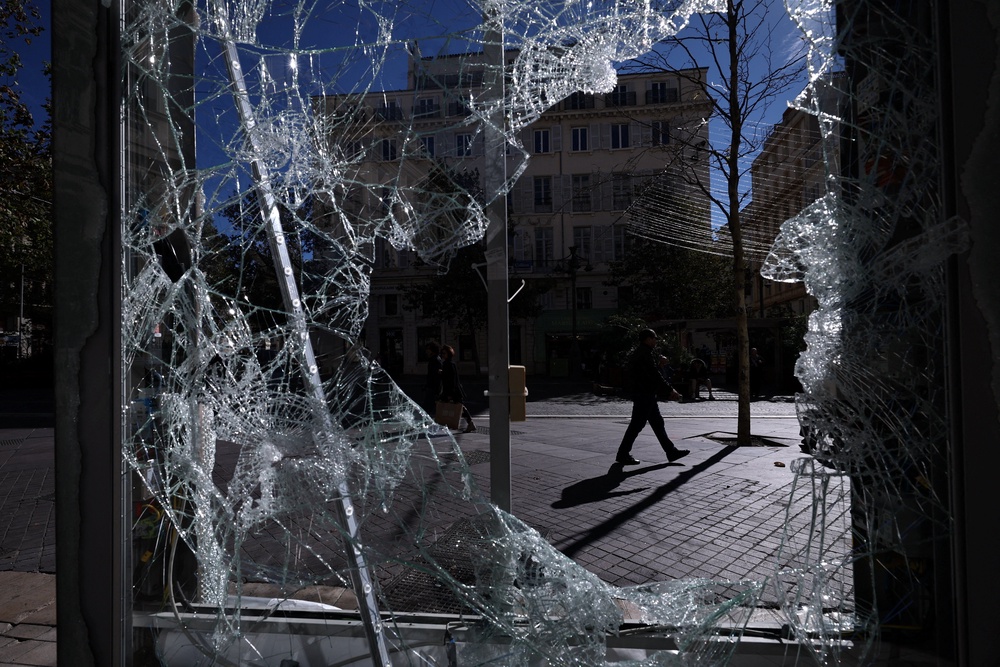 A person walking along a street is seen through a broken billboard in Marseille (Reuters)