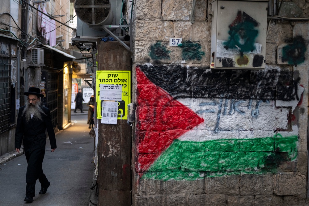 An ultra-Orthodox Jewish man walks past a Palestinian flag painted on a wall at the Mea Shearim neighbourhood in Jerusalem (AFP/Getty)