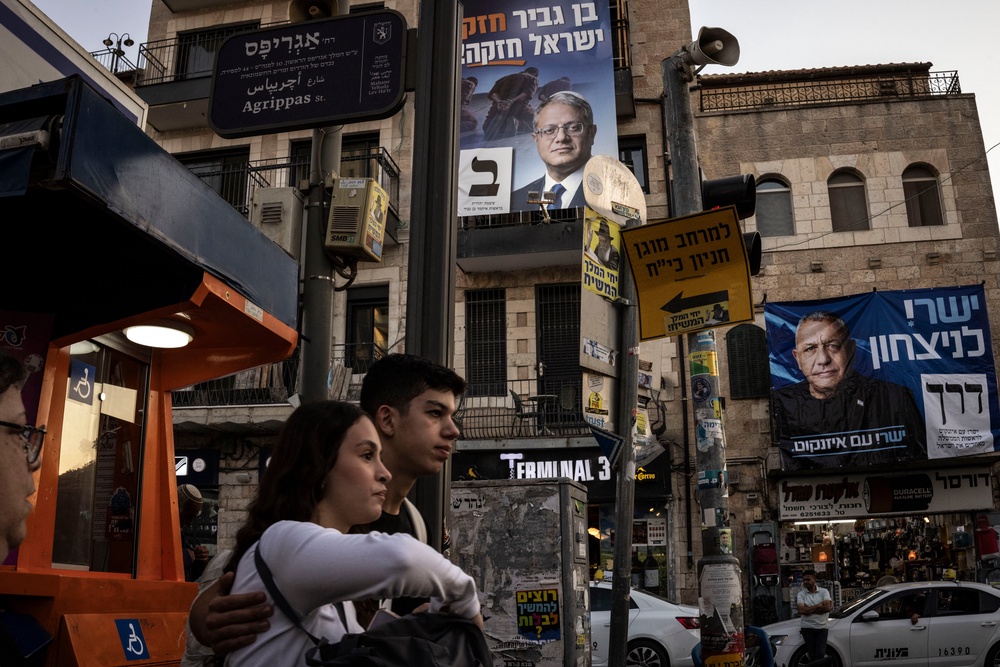 People walk past election campaign banners in the Ben Yehuda Market area of Jerusalem on Thursday 22 October (AFP/Getty)