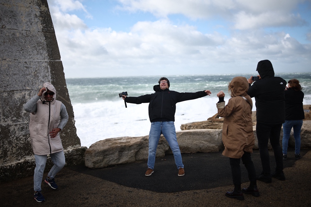 Members of the public brace themselves against the strong winds beside the breaking waves at Portland Bill, southern England on October 23, 2026, as Storm Austen brings strong winds and heavy rain across much of southern England (AFP/Getty)