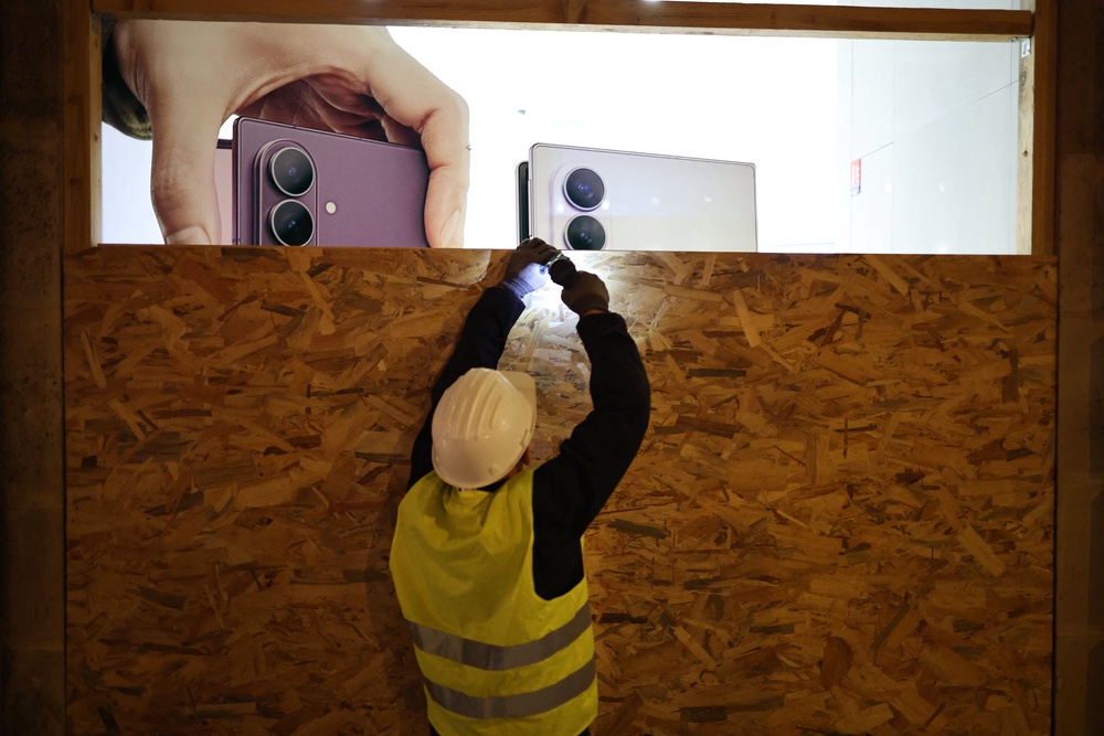A worker installs a wooden panel to board up the shop window of the Samsung store ahead of a demonstration planned (AFP/Getty)