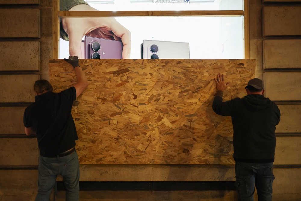 Workers install a wooden panel to board up the shop window of the Samsung store ahead of a demonstration planned (AFP/Getty)