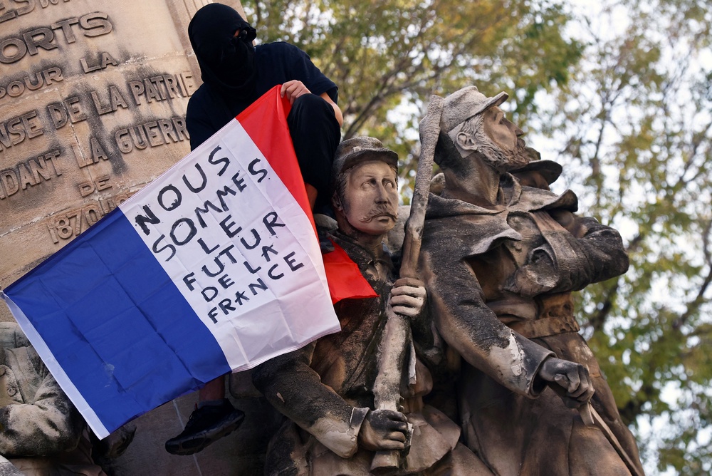 A protester holds a French flag reading 