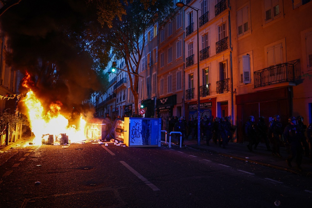 French riot police walk past a burning barricade during a demonstration in favor of purchasing power, the protection of public services, and fiscal and social justice, in Marseille (AFP via Getty Images)
