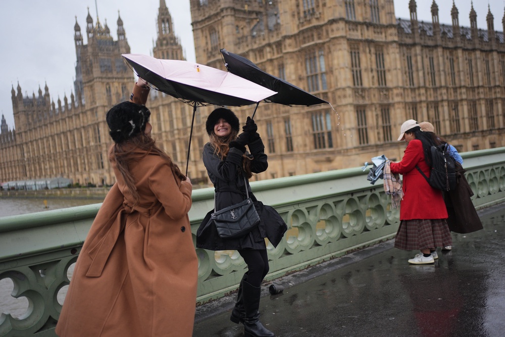 People in the rain on Westminster Bridge, London. An amber weather warning is in place across Scotland, the north of England down to Carlisle and the north-east of Northern Ireland on Saturday (PA)