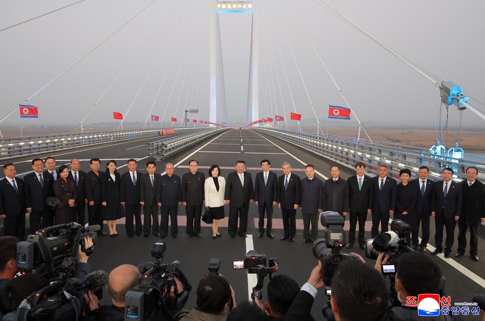 North Korean leader Kim Jong Un, Chinese People's Political Consultative Conference (CPPCC) Chairman Wang Huning, Chinese Foreign Minister Wang Yi, and North Korean Foreign Minister Choe Son Hui pose for a photograph with officials on the New Yalu River Bridge linking Dandong, Chin (Reuters)