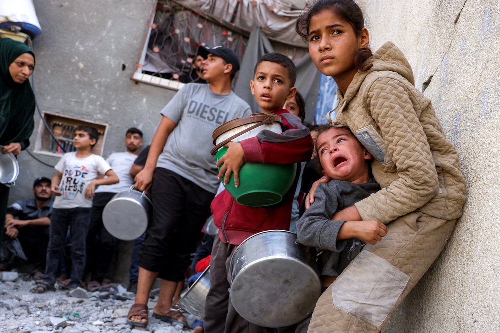 Palestinians take cover from a reported drone strike while they were queueing to receive meals from a charity kitchen in the Jabalia camp, on October 24 (AFP/Getty)