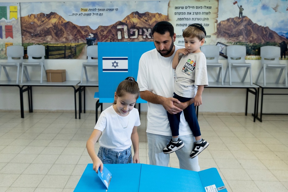 Sahar Mahluf, accompanied by his children Adir and Noya, casts his vote during Israel's general elections, in Hadera (Getty)