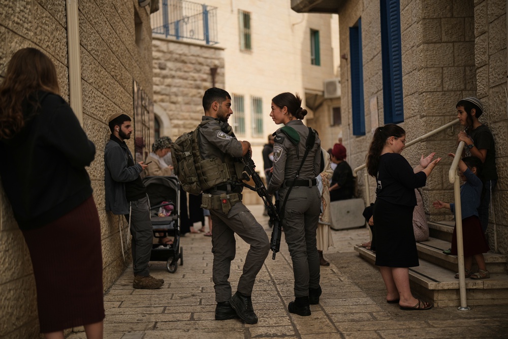 Israeli settlers and border police officers line up to vote outside a polling station in Hebron, in the West Bank (AP)