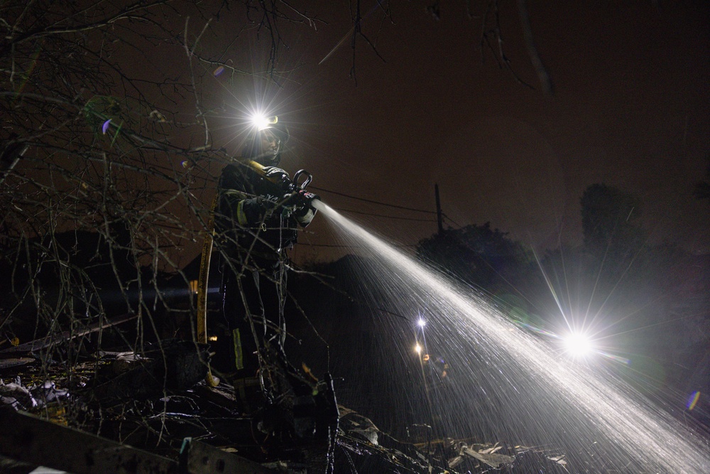A firefighter extinguishes smouldering debris in front of a destroyed private house in Kyiv, October 22 (Getty)