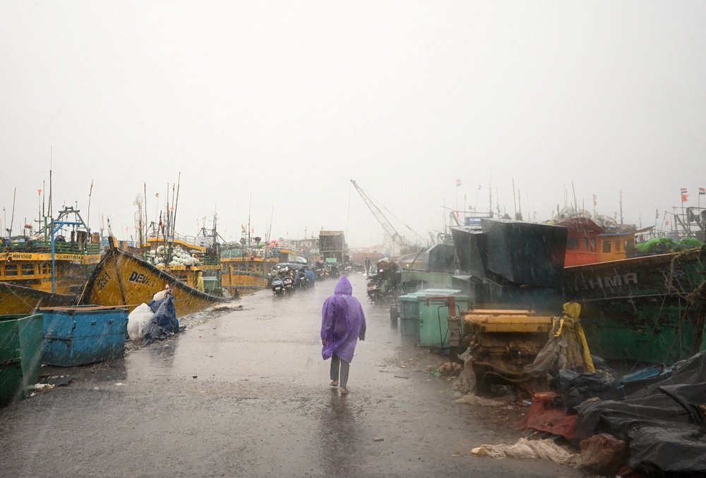 A man walks past docked boats along the harbour amid rain and gusty winds as Cyclone Arnab approaches, in Visakhapatnam, Andhra Pradesh, India, 27 October 2026 (Reuters)