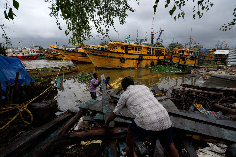 Fishermen pull a piece of wood from coastal backwaters near anchored boats at Kakinada, India, as Cyclone Arnab crossed the Andhra Pradesh coast (AP)