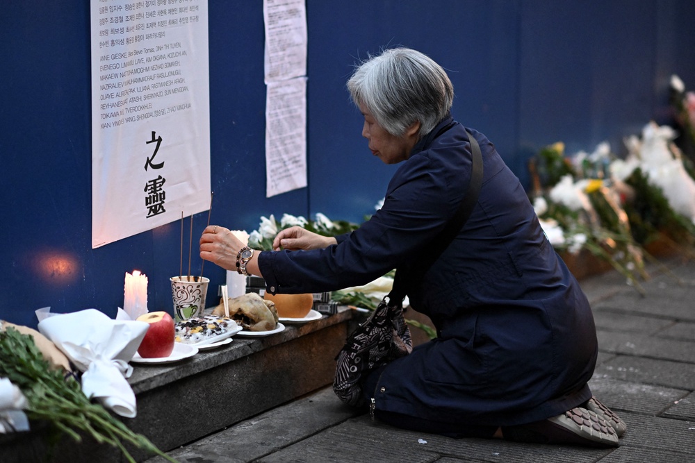 A woman burns incense to pay her respects on a wall in an alleyway in Seoul, the site of the tragic crowd crush that killed 159 people during Halloween celebrations, in Seoul's popular Itaewon nightlife area two years ago (AFP/Getty)