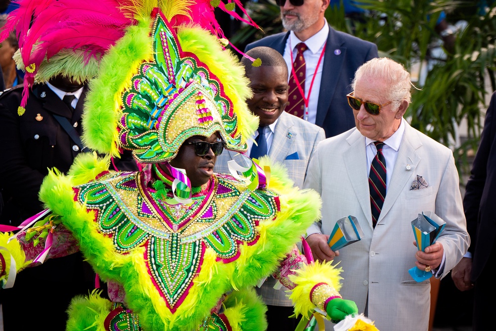 The King with a performer during the celebratory Junkanoo street parade (Aaron Chown/PA) (PA Wire)