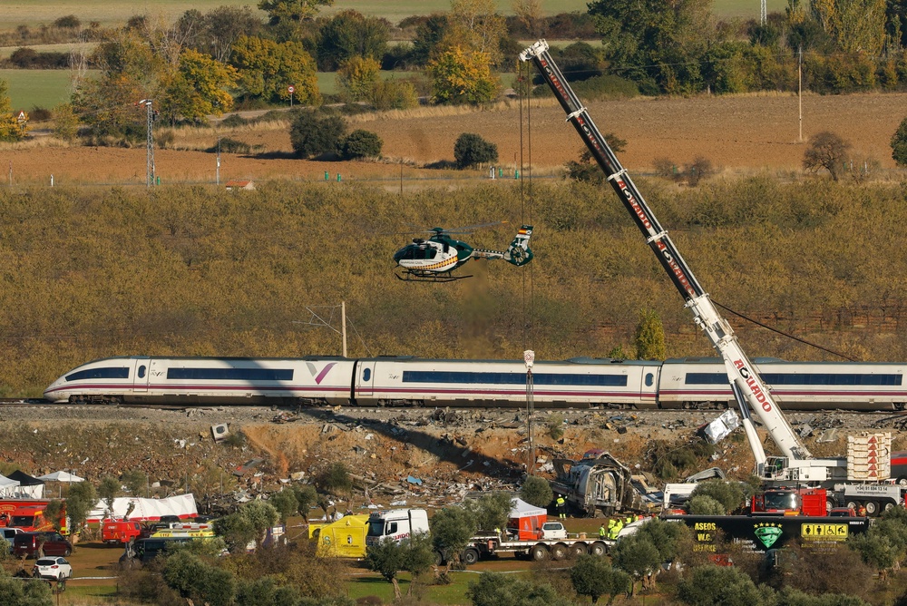 A Civil Guard helicopter hovers as emergency crews use heavy cranes to remove damaged carriages of a crash between two high-speed trains (AFP/Getty)