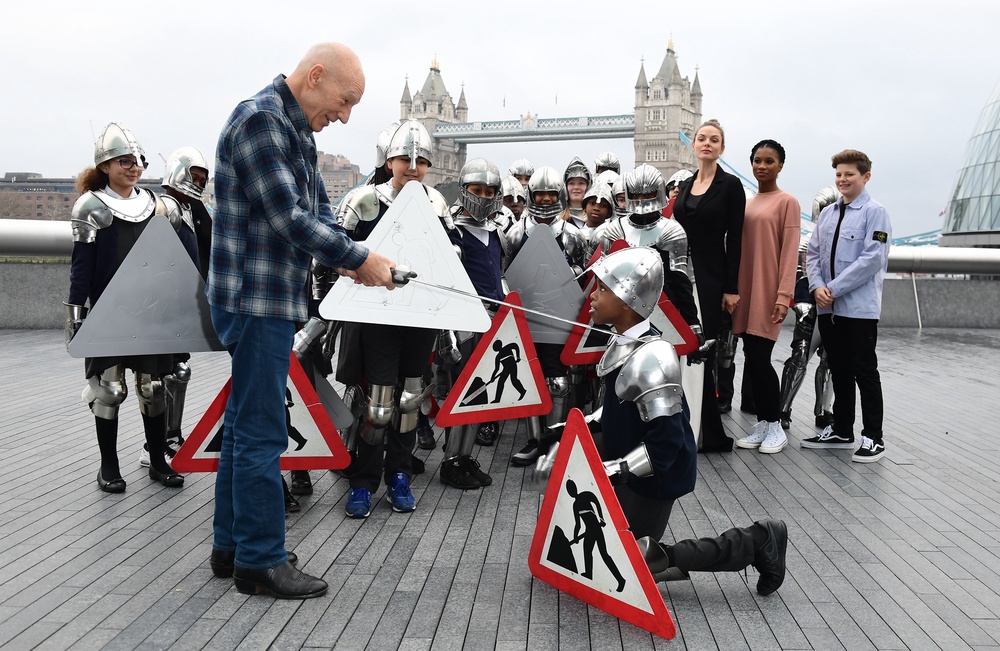 Rebecca Ferguson, Rhianna Dorris and Louis Ashbourne Serkis look on as Sir Patrick Stewart ‘knights’ pupils from Snowsfields Primary school and Tower Bridge Primary school at a photo call for cast members from The Kid Who Would Be King against the backdrop of Tower Bridge in 2019 (Archive/PA) (PA Archive)